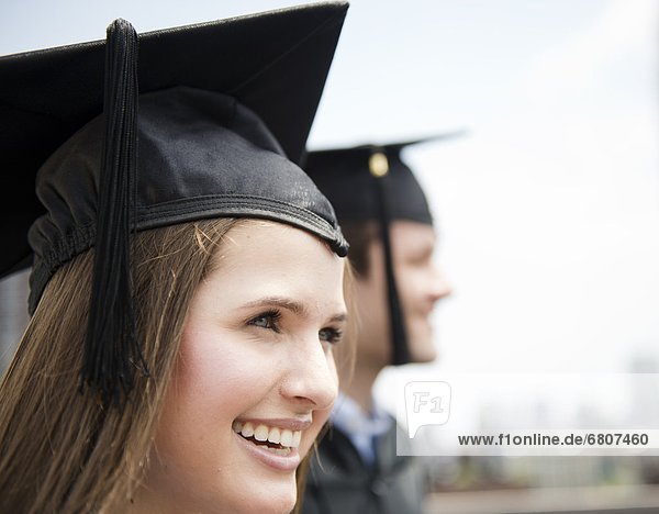 Profiles of young man and woman wearing graduation gowns