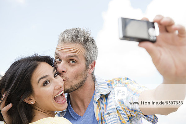 Kissing his girlfriend by taking surprise picture with mobile phone