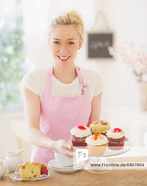 junge Frau junge Frauen lächeln halten Schürze Kuchenplatte