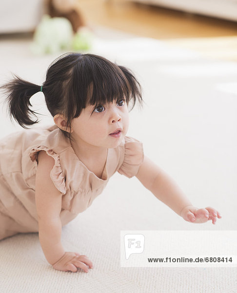 Portrait of baby girl (12-17 months) crawling on carpet