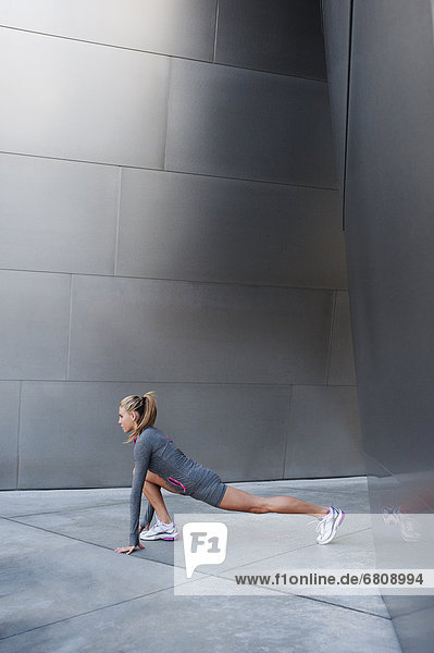 USA  California  Los Angeles  Young woman stretching near modern building