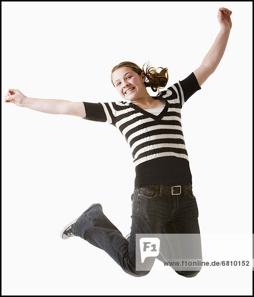 Studio shot of girl (12-13) jumping with arms raised