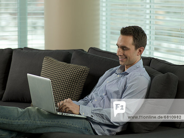 Man sitting on sofa using computer