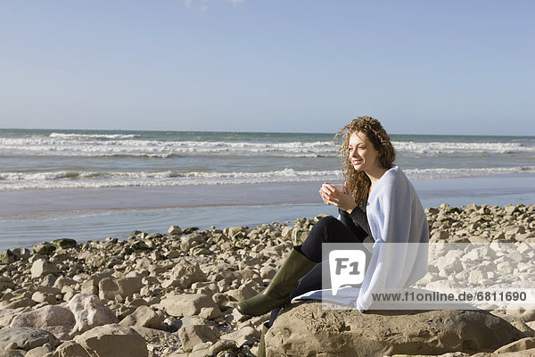 France  Pas-de-Calais  Escalles  Woman wrapped in blanket sitting on rocky beach