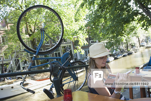 Holland  Amsterdam  Woman with guidebook sitting by canalside
