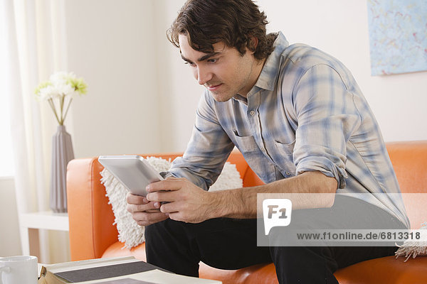 sitzend benutzen Mann Couch jung Tablet PC