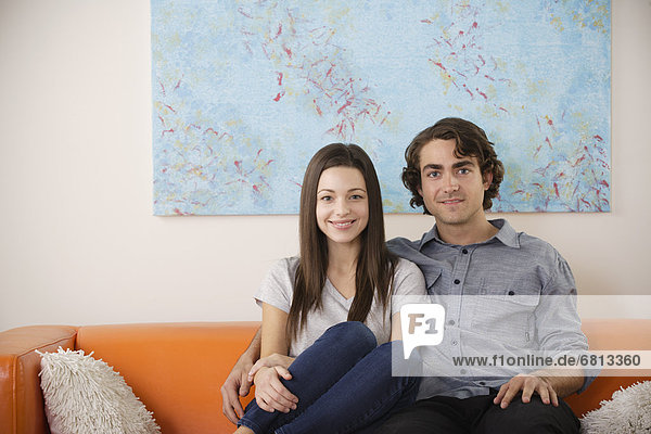 Portrait of young couple sitting on sofa