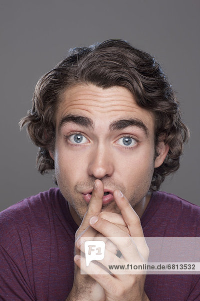 Studio shot of young man with finger on his lips