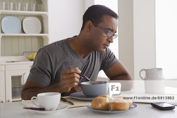 Mann  reifer Erwachsene  reife Erwachsene  essen  essend  isst  Frühstück  Zeitung  vorlesen