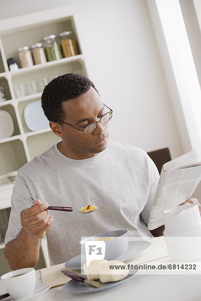 Mann Mittelpunkt essen essend isst Erwachsener Frühstück Zeitung vorlesen