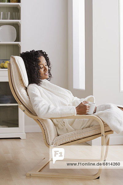 Woman drinking coffee in armchair in morning