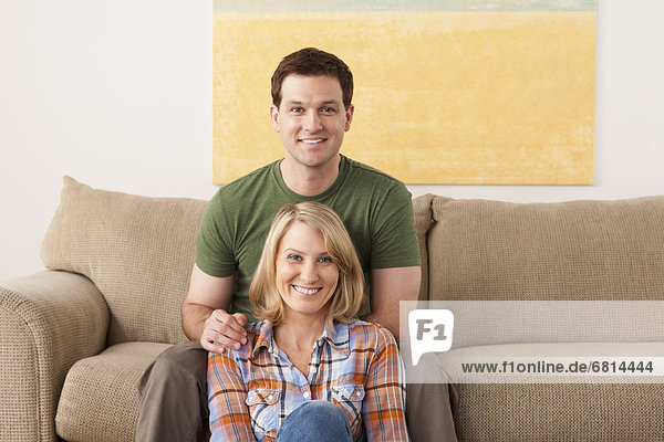 Smiling mid adult couple sitting on sofa