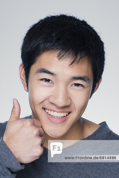 Studio portrait of young man showing thumbs up sign