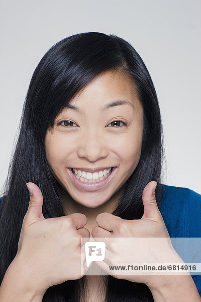 Studio portrait of young woman showing thumbs up sign