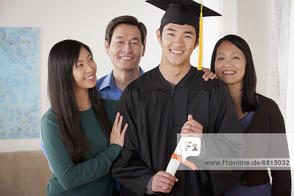 Portrait of young man in graduation gown with family