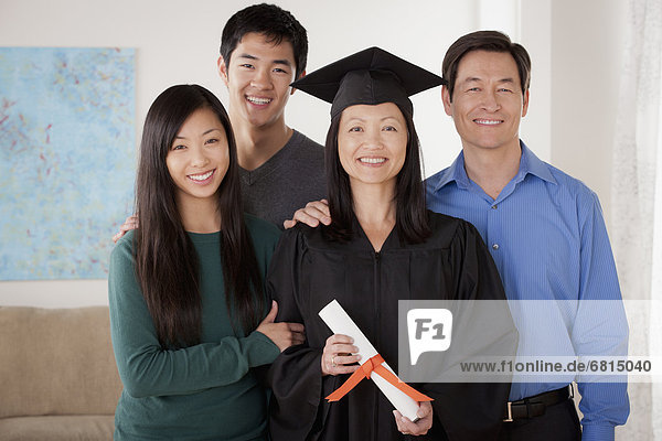 Portrait of young man in graduation gown with family