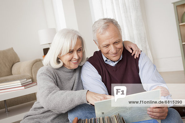 Smiling senior couple looking at vinyl's in living room