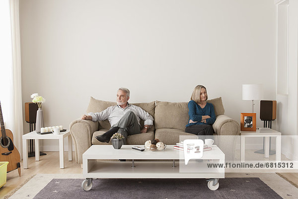 Angry senior couple sitting on sofa
