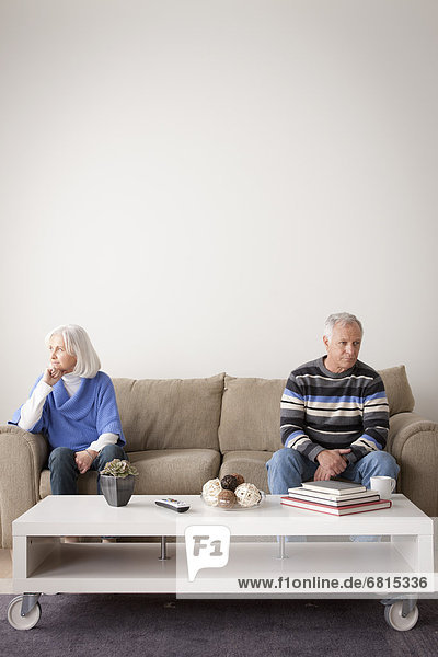Angry senior couple sitting on sofa