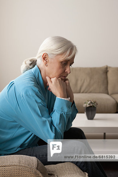 Sad senior woman sitting on armchair
