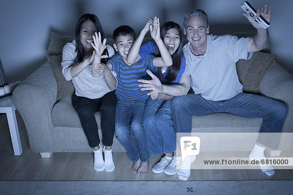 Family sitting on sofa and watching television