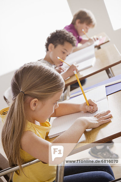 Schoolchildren focused on writing in classroom