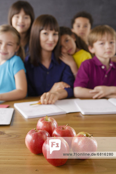 Teacher with group of pupils and apples on desk