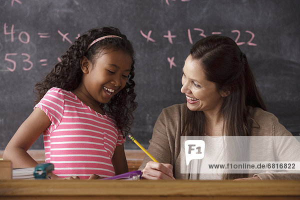 Schoolgirl (10-11) and teacher with blackboard in background