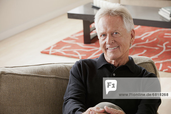 Portrait of smiling senior man sitting on sofa