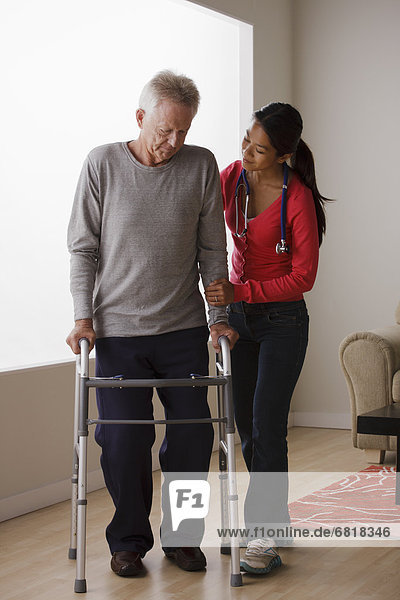 Young female nurse taking care of senior man with walker