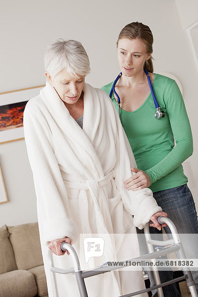 Young female nurse taking care of senior woman with walker