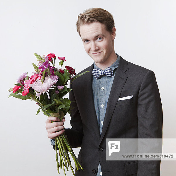 Portrait of young handsome man holding bunch of flowers
