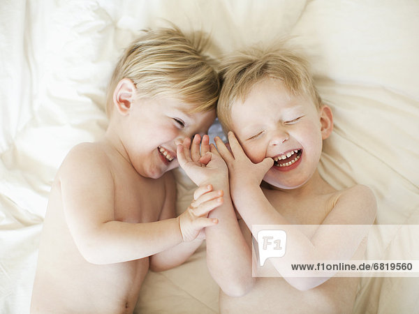 Two toddler boys (2-3) messing about in bed
