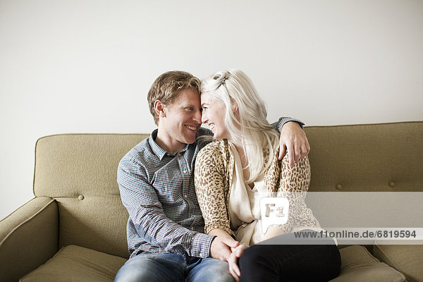 Happy young couple embracing on sofa