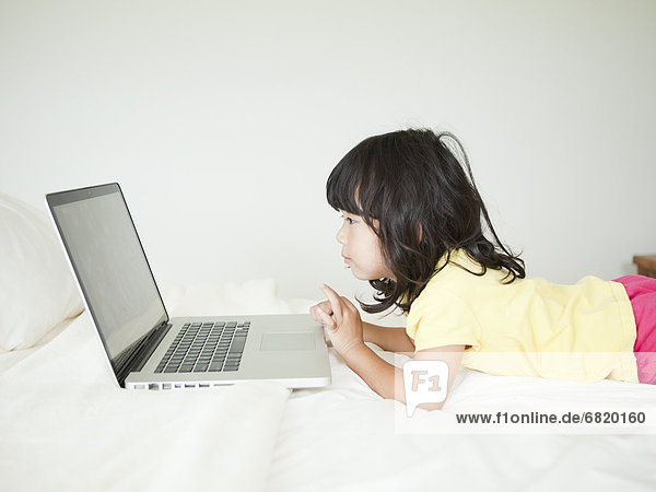 Girl lying down in bed  using laptop (4-5)