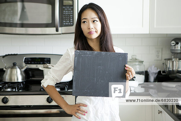 junge Frau junge Frauen einsteigen lächeln Küche halten schwarz