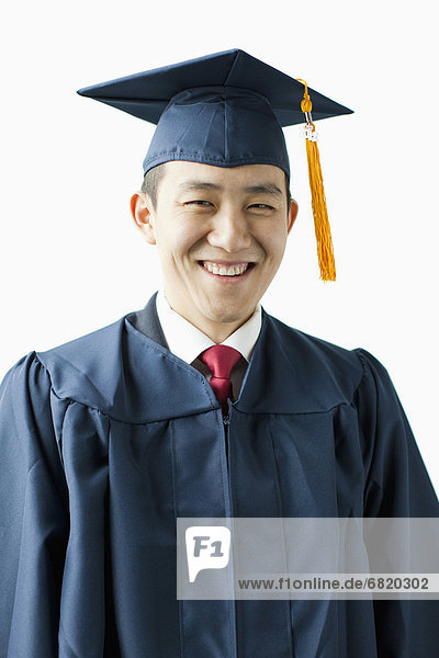 Portrait of young man in graduation gown  studio shot