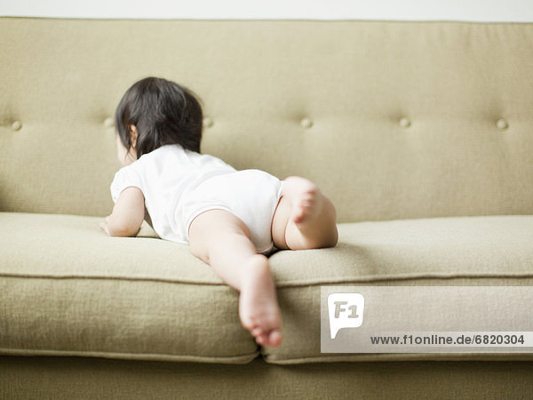 Baby girl (12-17 months) crawling on sofa