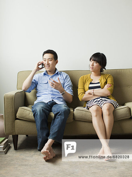 Young couple sitting on sofa  man talking via mobile