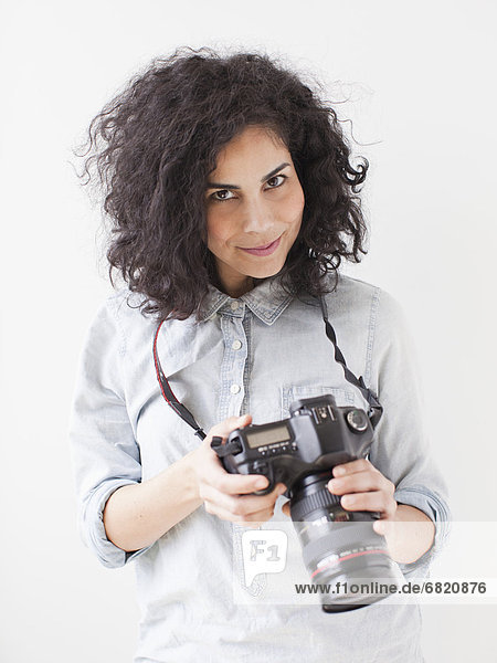Portrait of beautiful young woman holding professional camera
