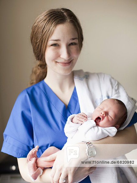 Portrait of young female nurse holding baby boy (2-5 months)