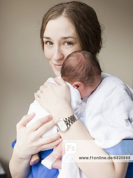Portrait of young female nurse holding baby boy (2-5 months)