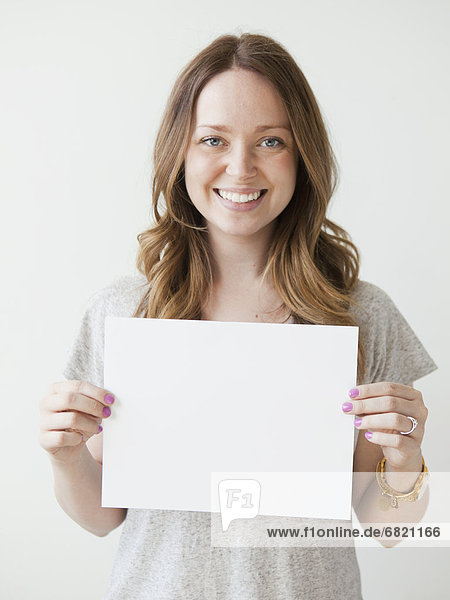 Portrait of serene young woman holding blank card