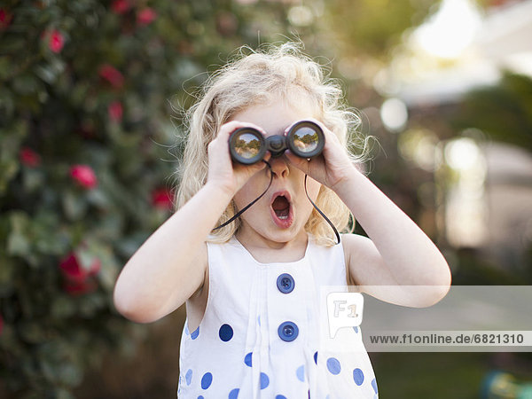 Surprised young girl (4-5) looking through binoculars