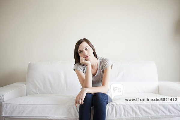 Bored young woman sitting on bed