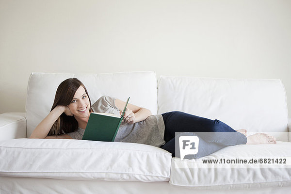 Young woman reclining on bed  reading book