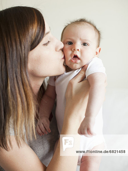 Mother kissing baby girl (2-5 months)