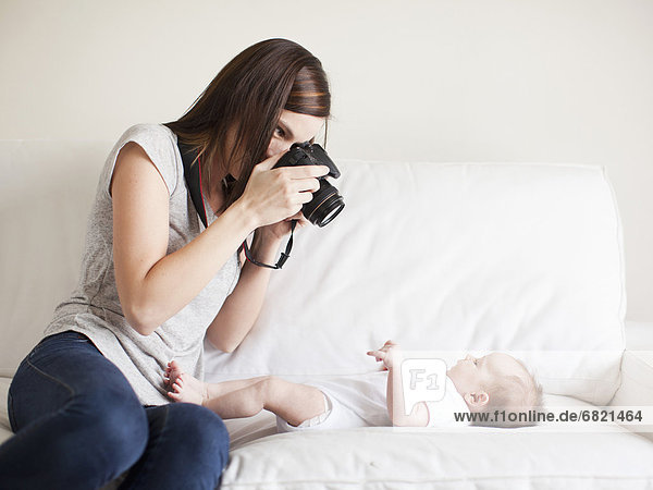 Mother photographing baby girl (2-5 months)