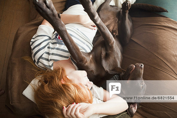 Young woman and her dog sleeping on sofa