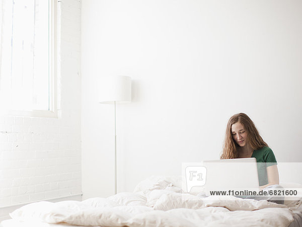 Young attractive woman using laptop in bed